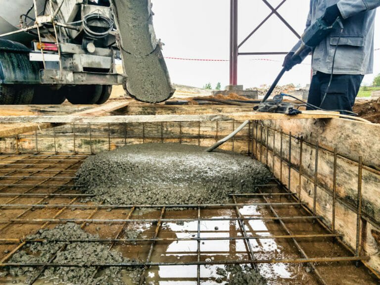worker poring concreate in industrial foundation - preparing the foundation and site for machinery installation