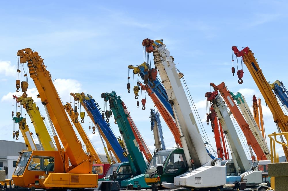 multiple cranes standing in area - Hydraulic vs. Pneumatic Heavy Equipment Lift Systems