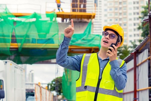worker guiding crane operator during rigging operation - effective communication protocols between crane operators and riggers
