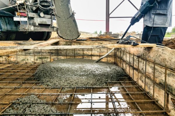 worker poring concreate in industrial foundation - preparing the foundation and site for machinery installation